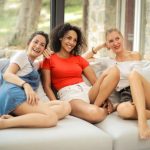 photo-of-three-laughing-woman-sitting-on-white-couch-3764547